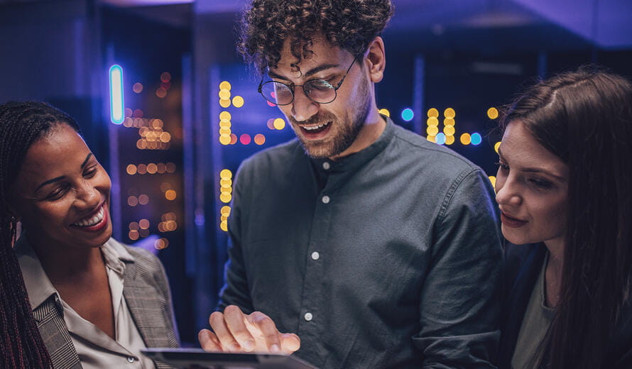 man with glasses on a tablet with two other women