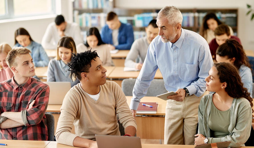 Mature professor using digital tablet while communicating with his students at college classroom.