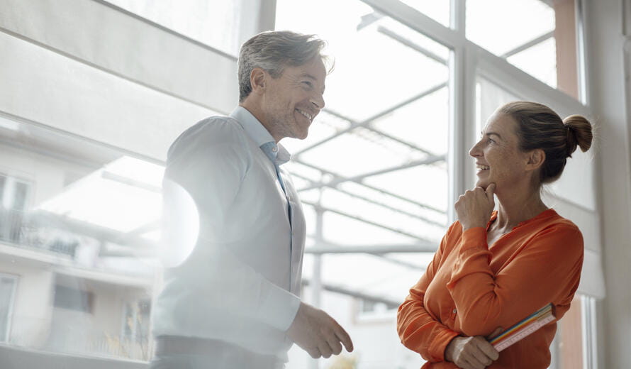 Businesswoman standing with hand on chin looking at colleague in office