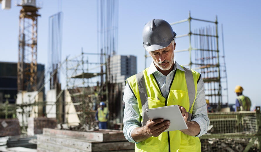 Male architect using digital tablet at construction site against clear sky