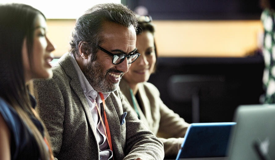 Smiling mature businessman looking at laptop at business meeting