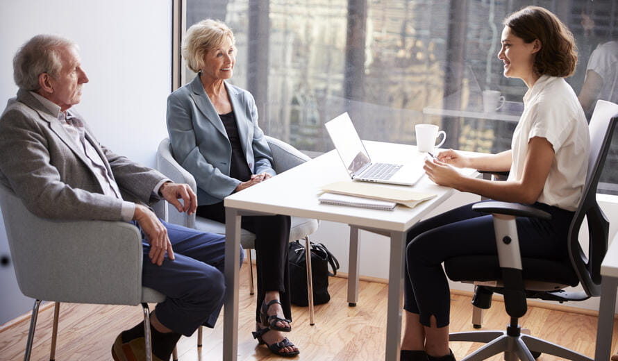 Smiling Senior Couple Meeting With Female Financial Advisor In Office