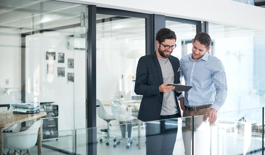 two men looking down at a tablet